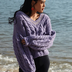 woman with a purple v neck sweater on the beach